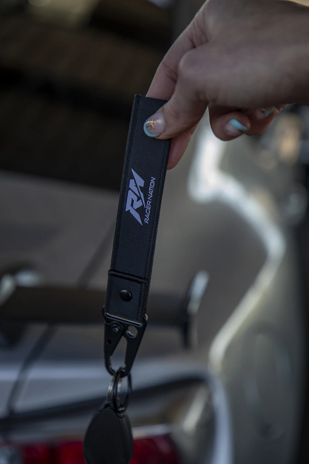 Black Racer Nation fabric keyring featuring the white RN logo and black metal clip.
