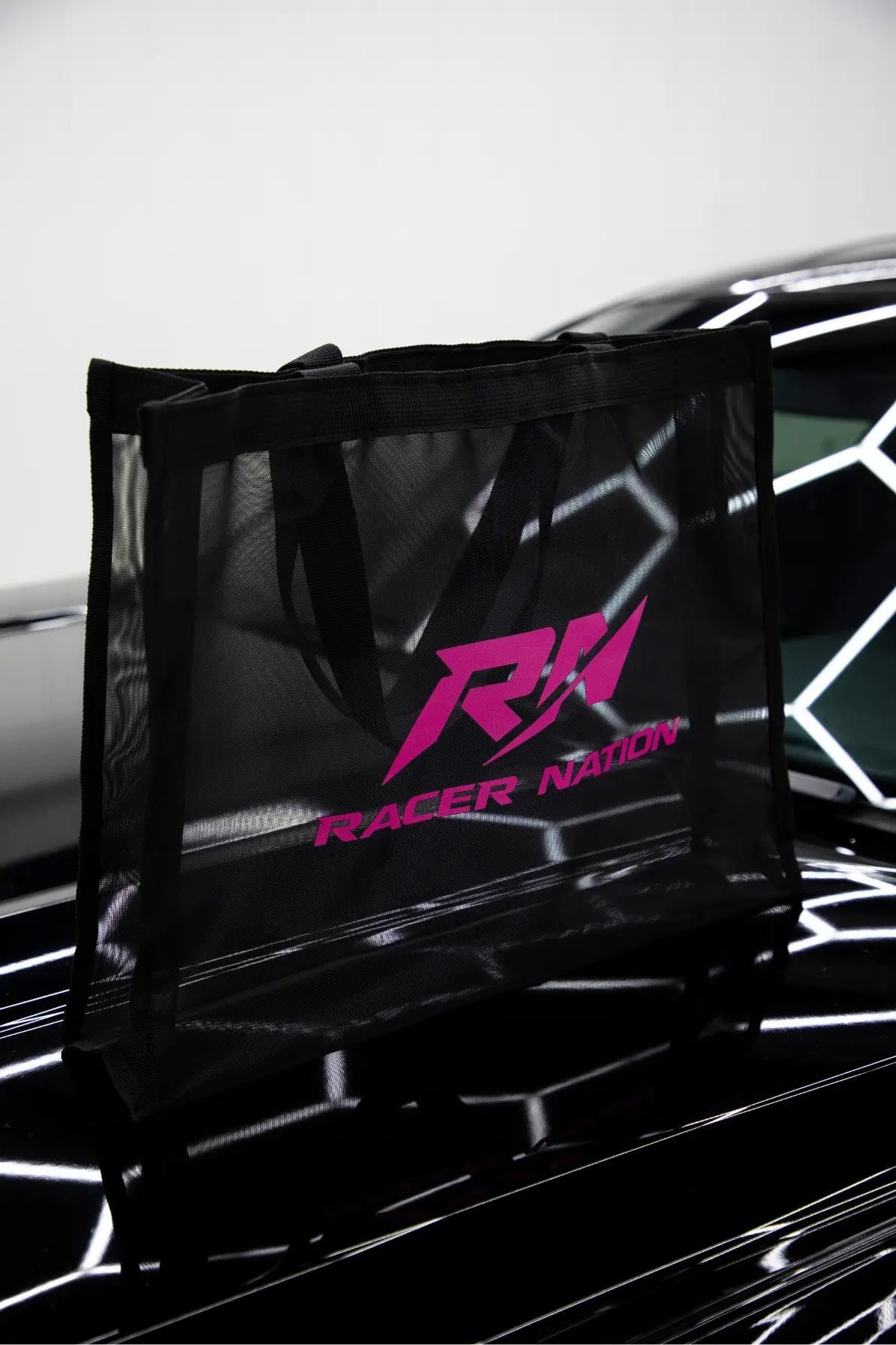Side view of the black Racer Nation mesh tote bag featuring the pink RN logo.