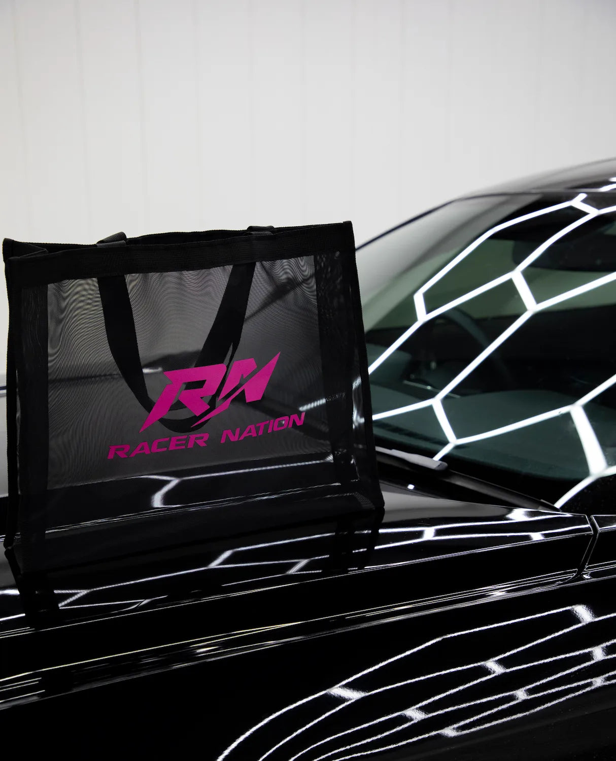 Black Racer Nation mesh tote bag with pink RN logo displayed on the bonnet of a black car.