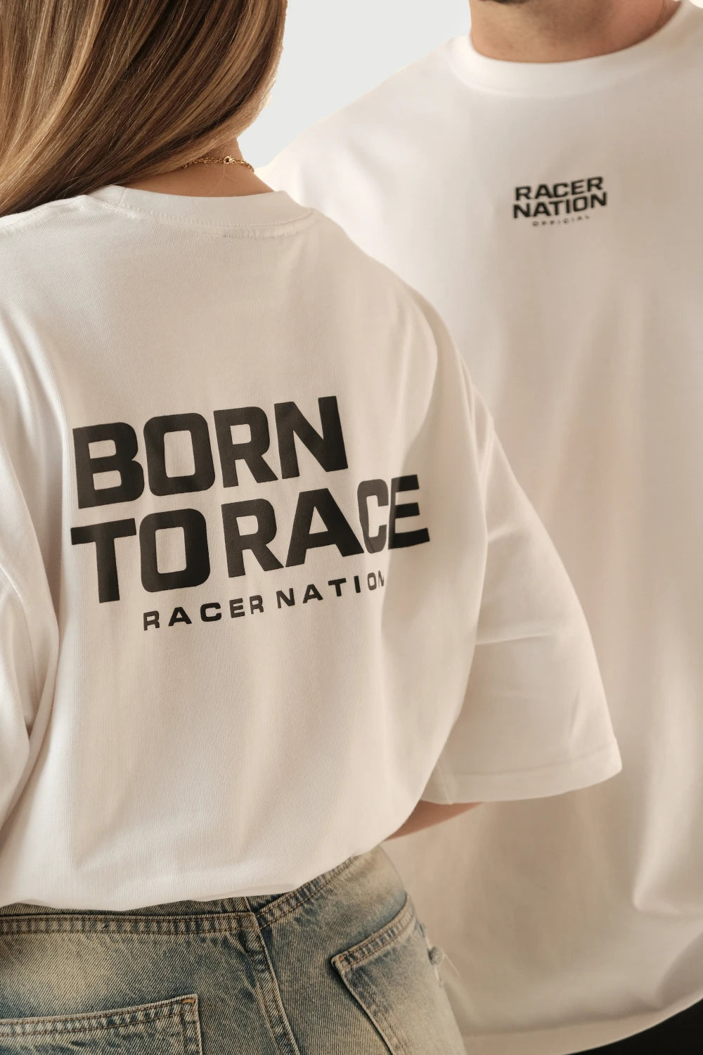 Close-up of Racer Nation Born To Race white oversized tee showing front chest logo and large black back graphic