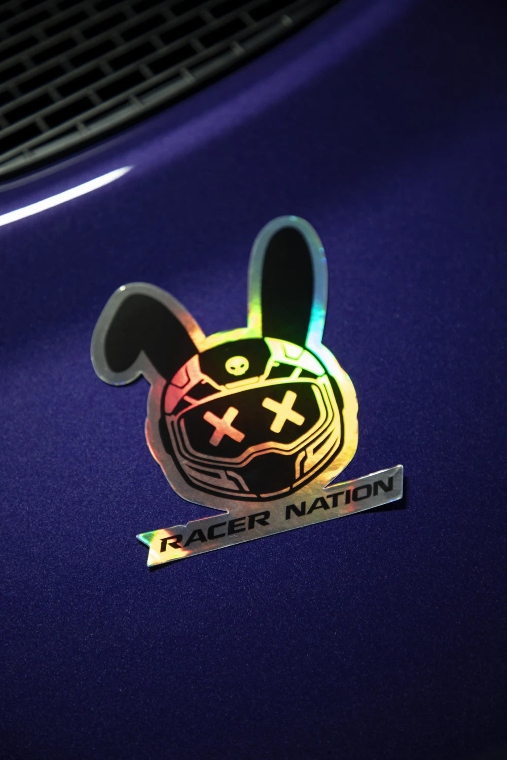 Holographic Racer Nation bunny helmet sticker displayed on the bonnet of a purple car, showing its reflective rainbow finish.