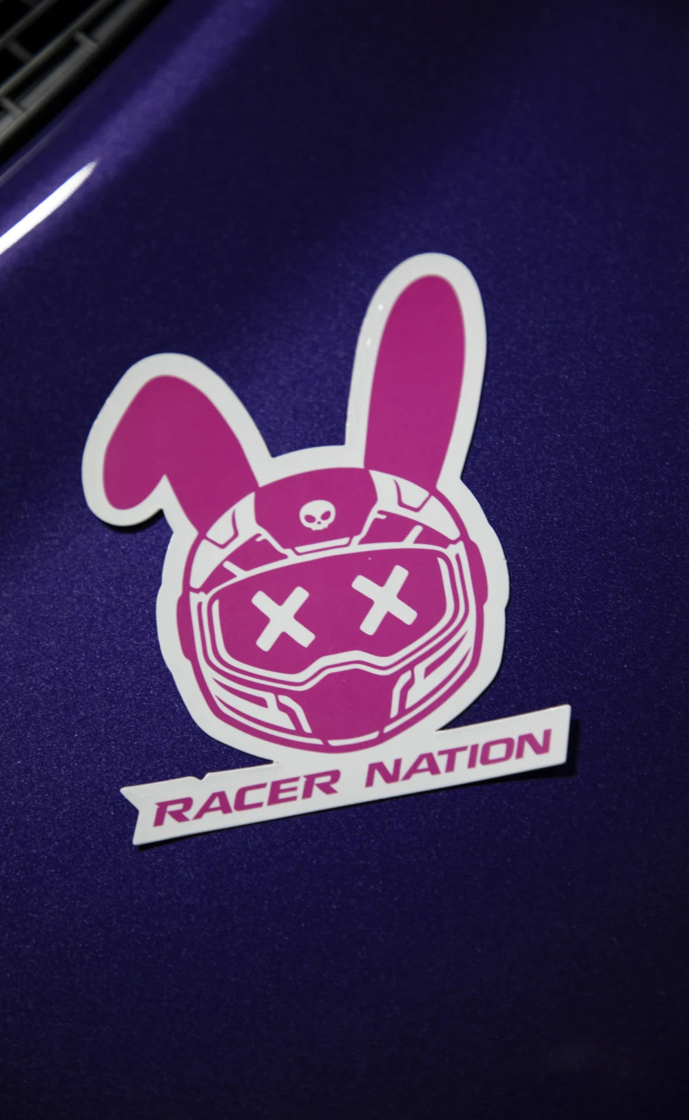 Pink and white Racer Nation bunny helmet sticker displayed on the bonnet of a purple car.
