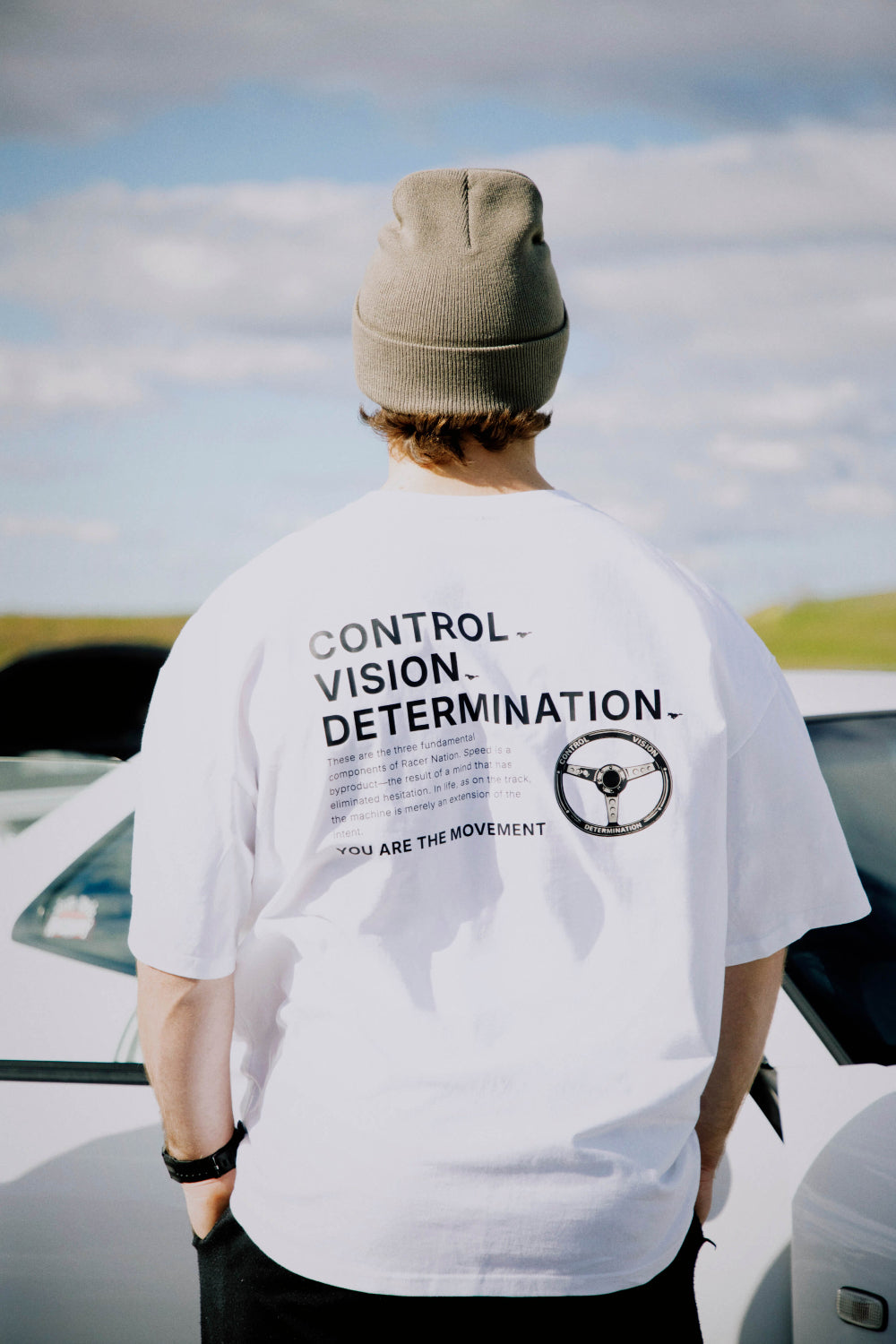 Back view of the Racer Nation Full Focus white oversized tee featuring a steering wheel graphic.