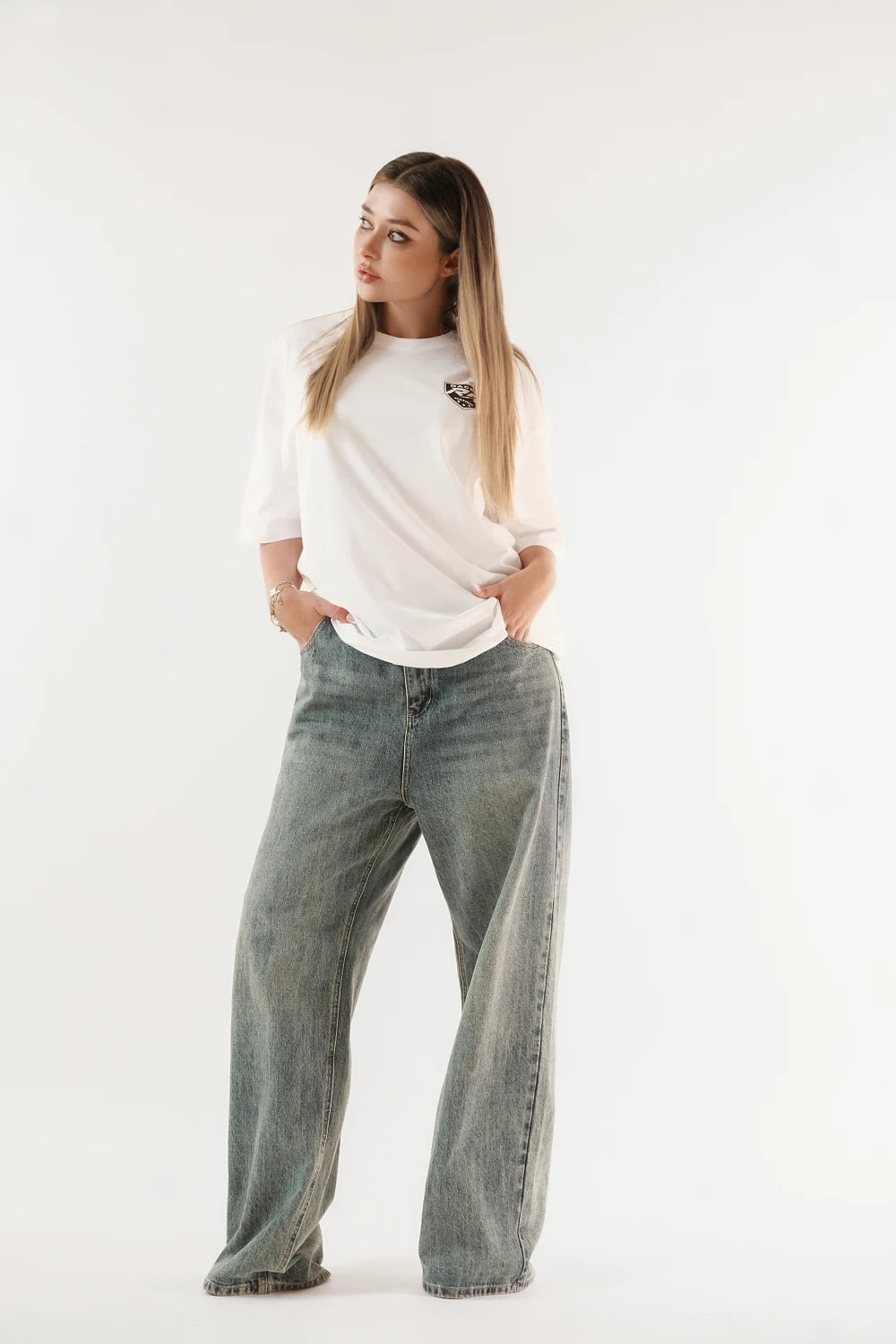 Female model wearing Racer Nation Full Focus white oversized tee showing black front chest graphic and relaxed oversized fit
