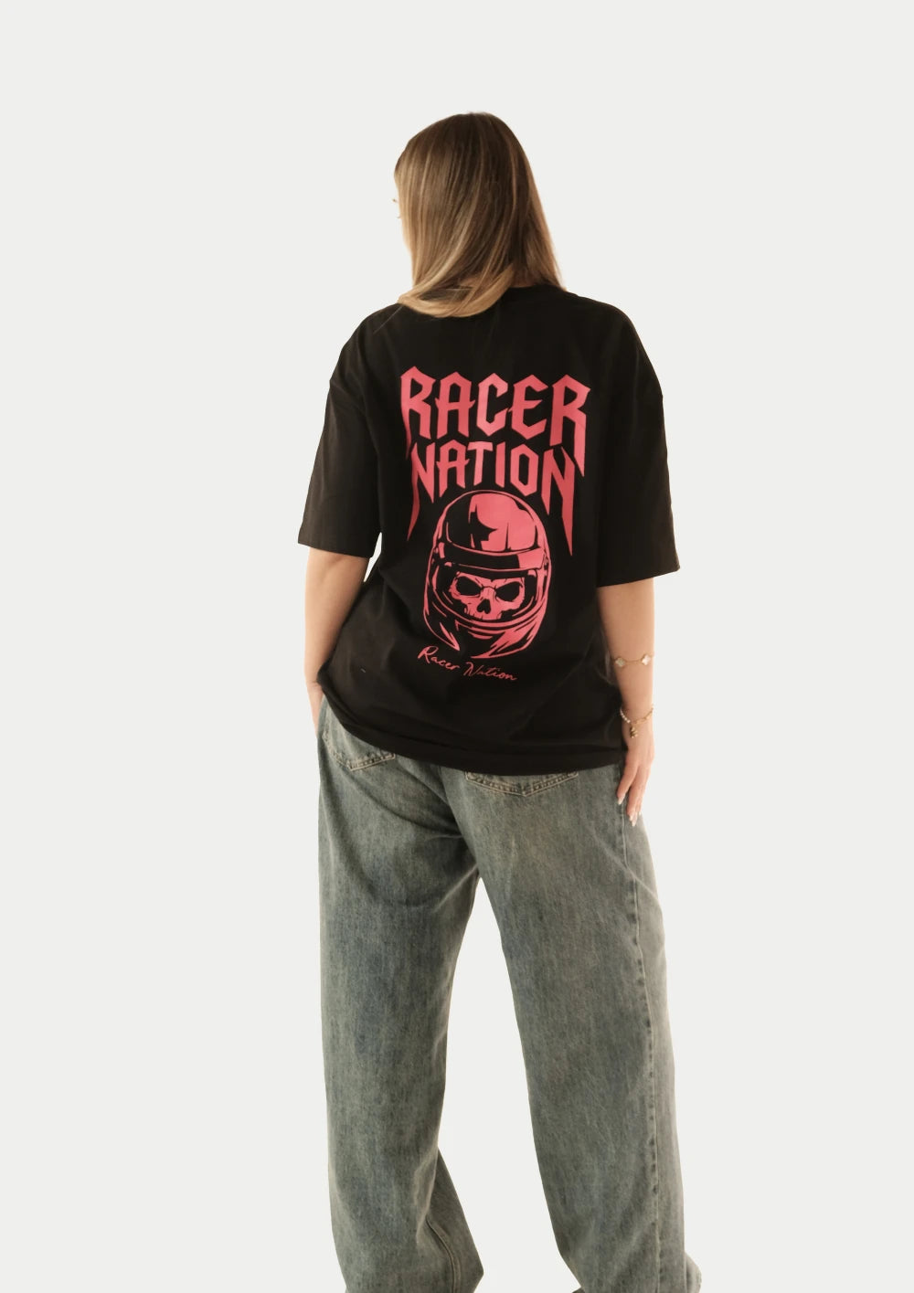Female model wearing Racer Nation Ghost Rider black oversized tee showing large red Racer Nation helmet back graphic
