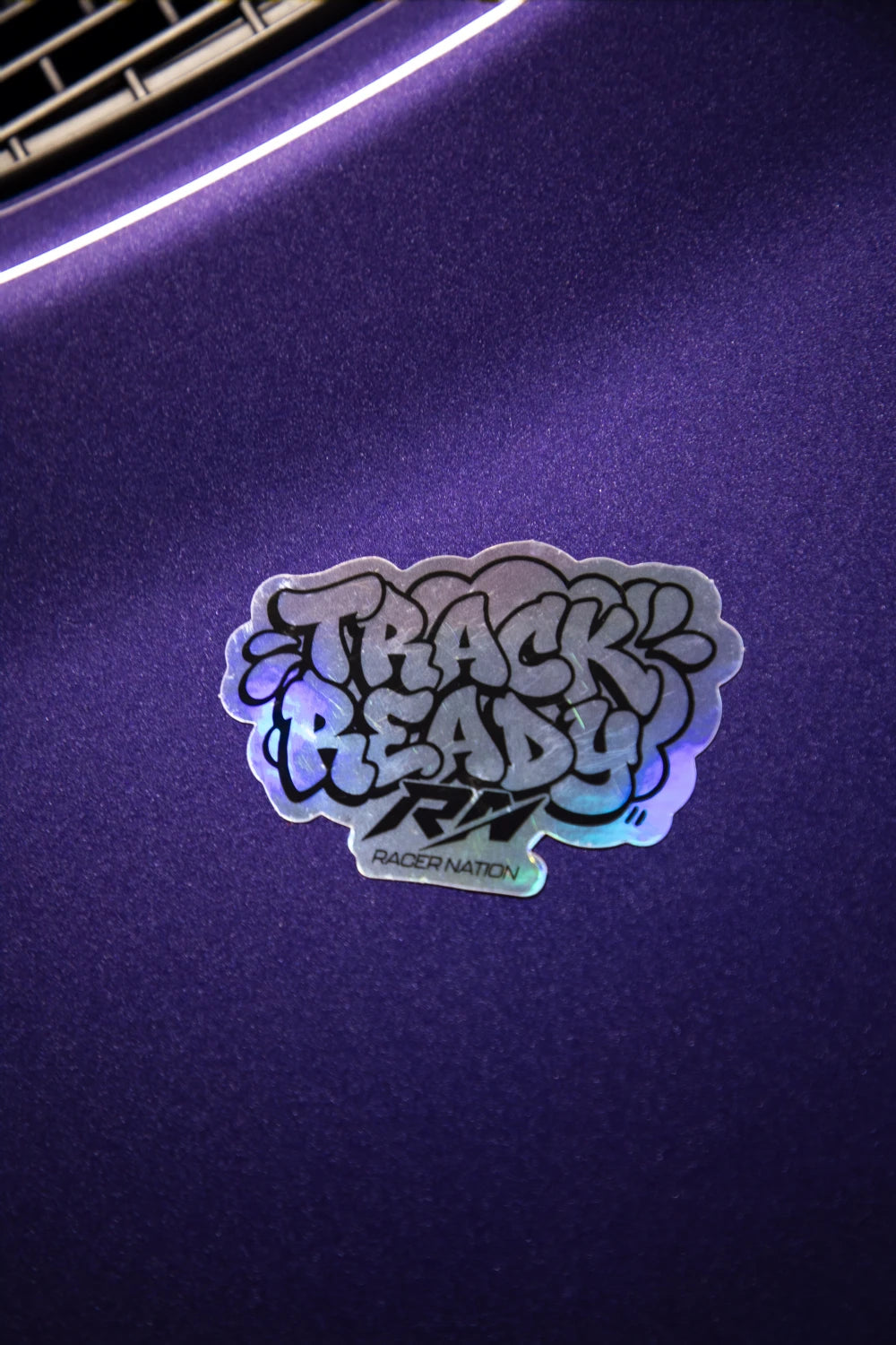 Holographic Racer Nation Track Ready sticker displayed on a purple car, showing its reflective finish.