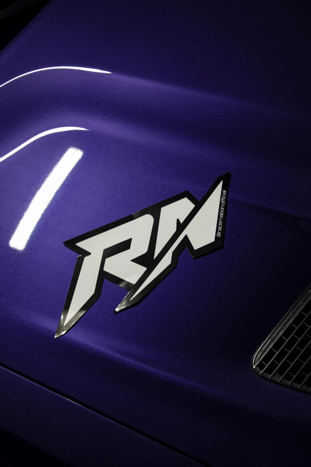 Large black and white Racer Nation RN logo sticker displayed on the bonnet of a purple car.