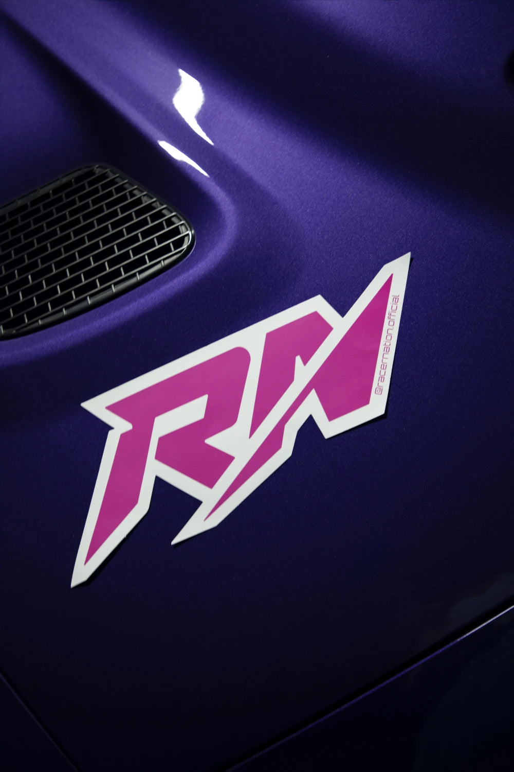 Large pink and white Racer Nation RN logo sticker displayed on the bonnet of a purple car.