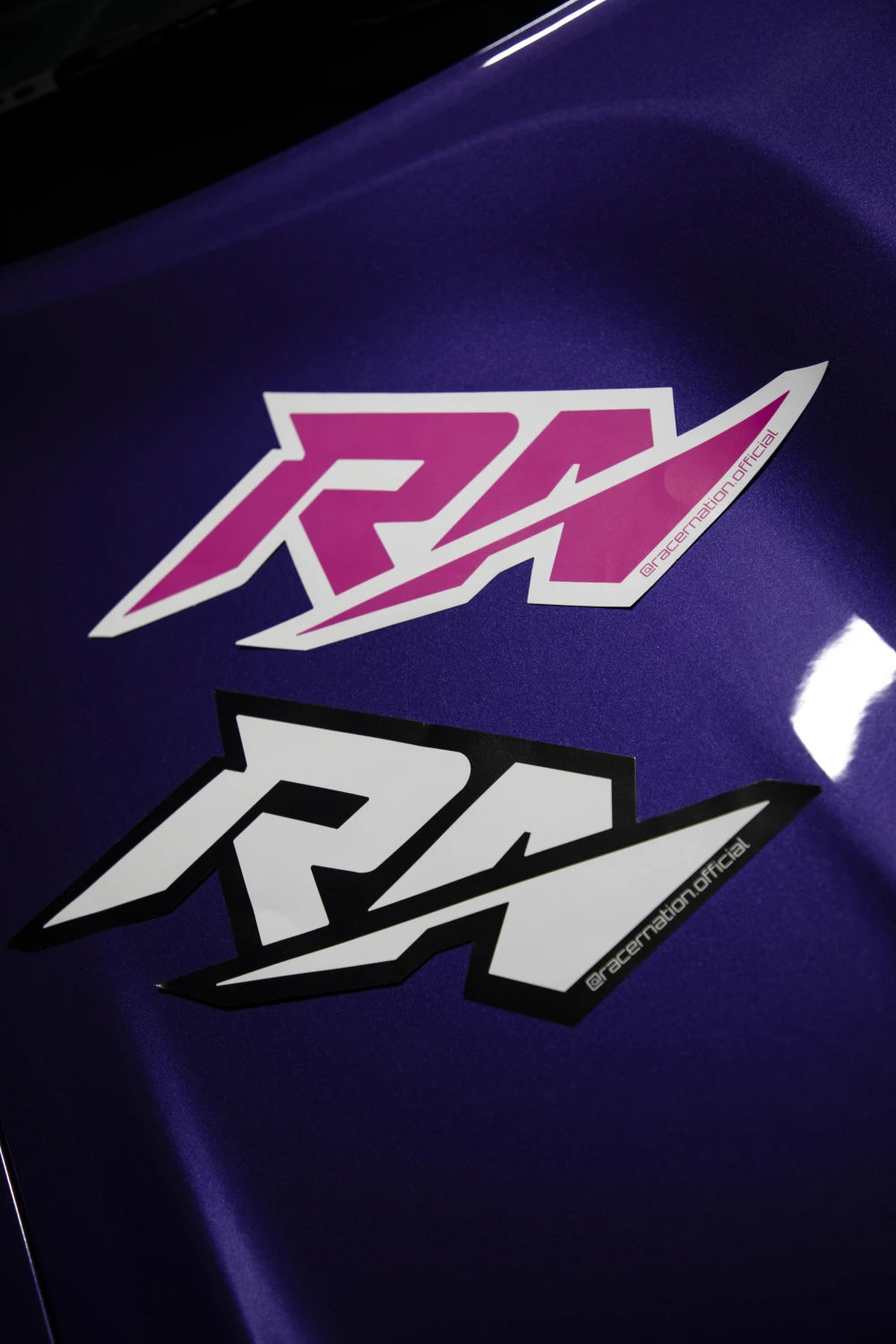 Large Racer Nation RN logo stickers in pink and white and black and white displayed on a purple car.