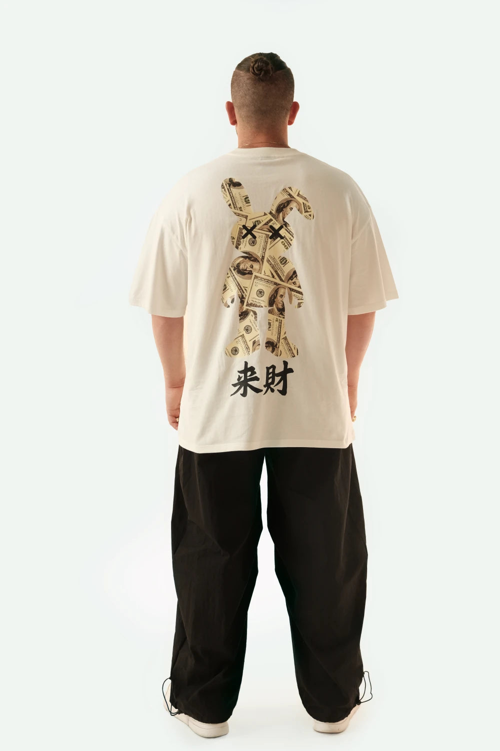 Male model wearing Racer Nation Money Bunny white oversized tee showing large black and gold money bunny back graphic