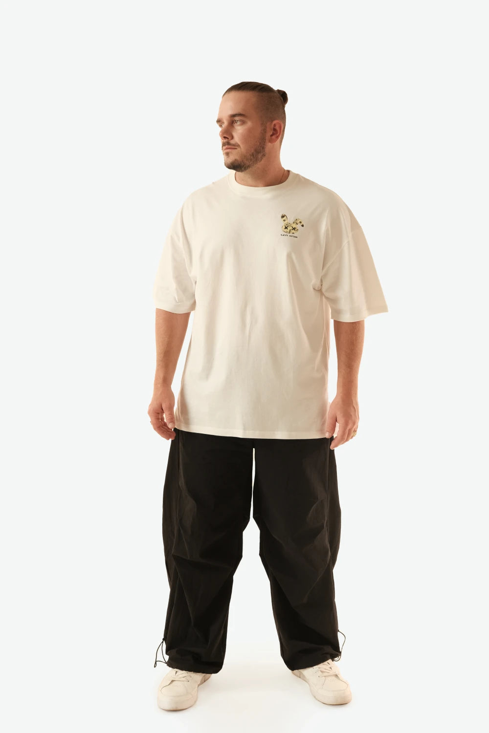 Male model wearing Racer Nation Money Bunny white oversized tee showing small black and gold bunny chest graphic and relaxed fit