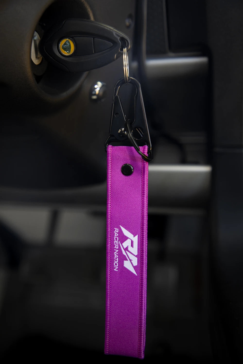 Purple Racer Nation fabric keyring with white RN logo attached to a set of car keys.