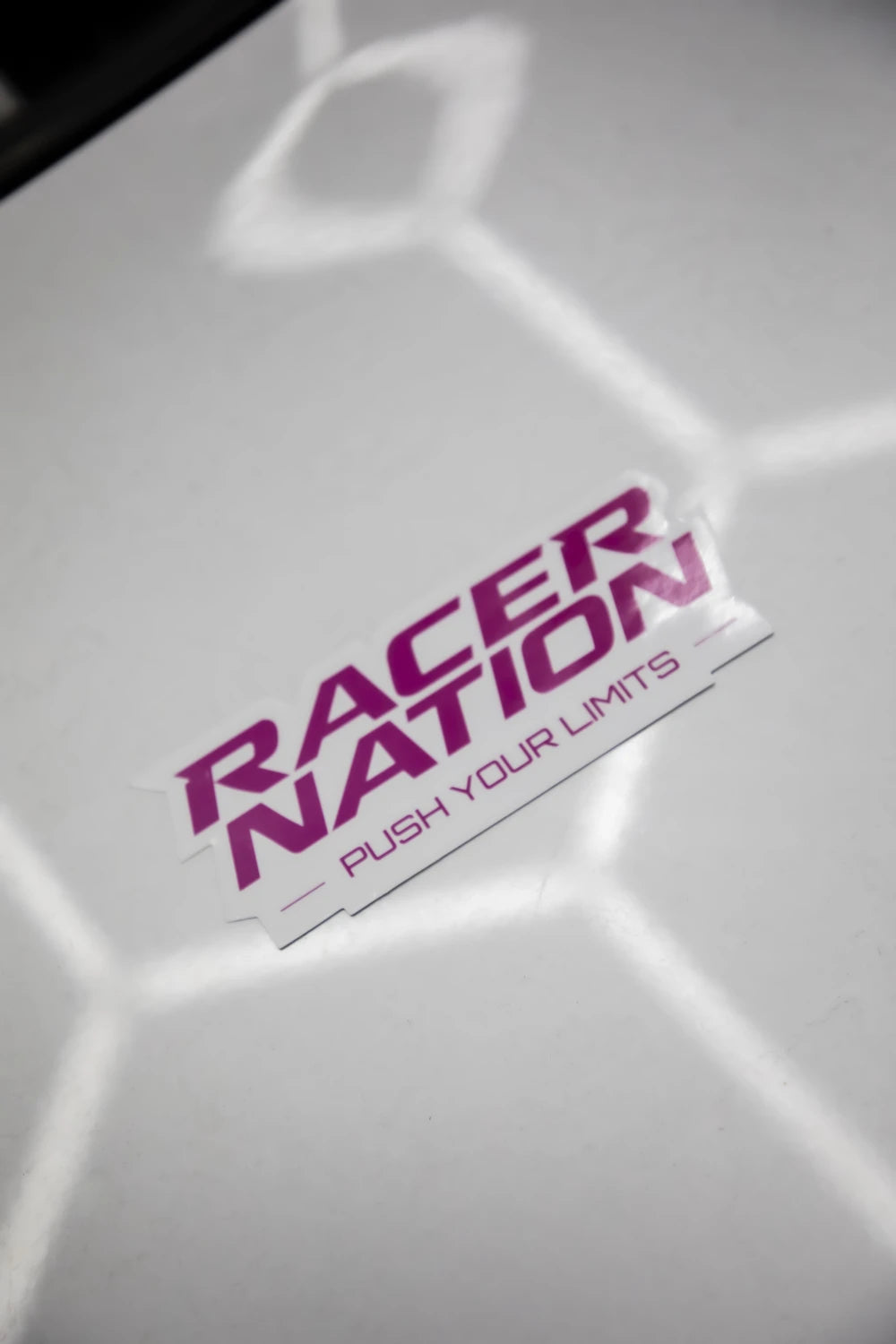 Pink and white Racer Nation Push Your Limits die cut sticker displayed on a white surface.