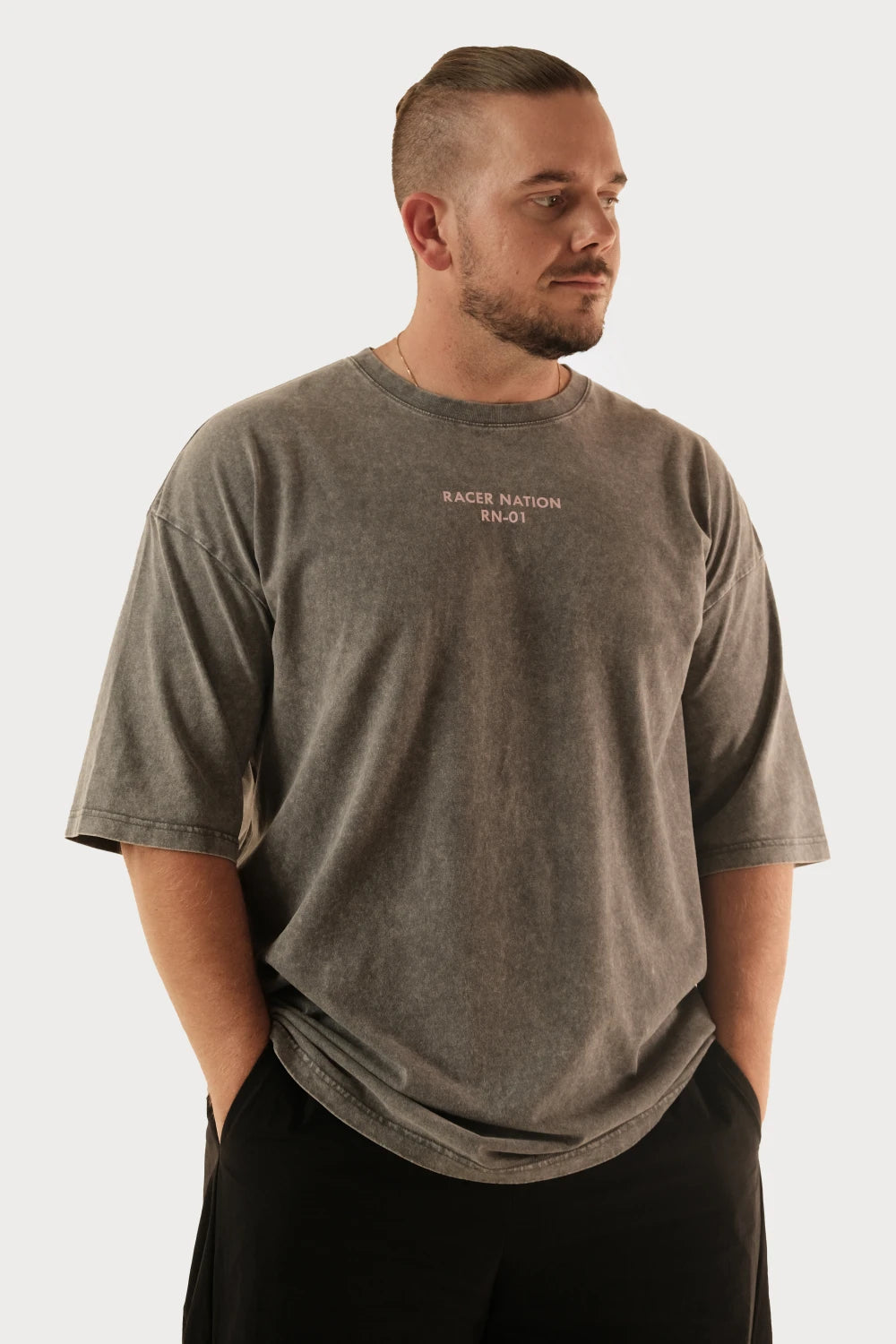 Male model wearing Racer Nation RN 01 grey acid washed oversized tee showing small front chest logo and relaxed fit