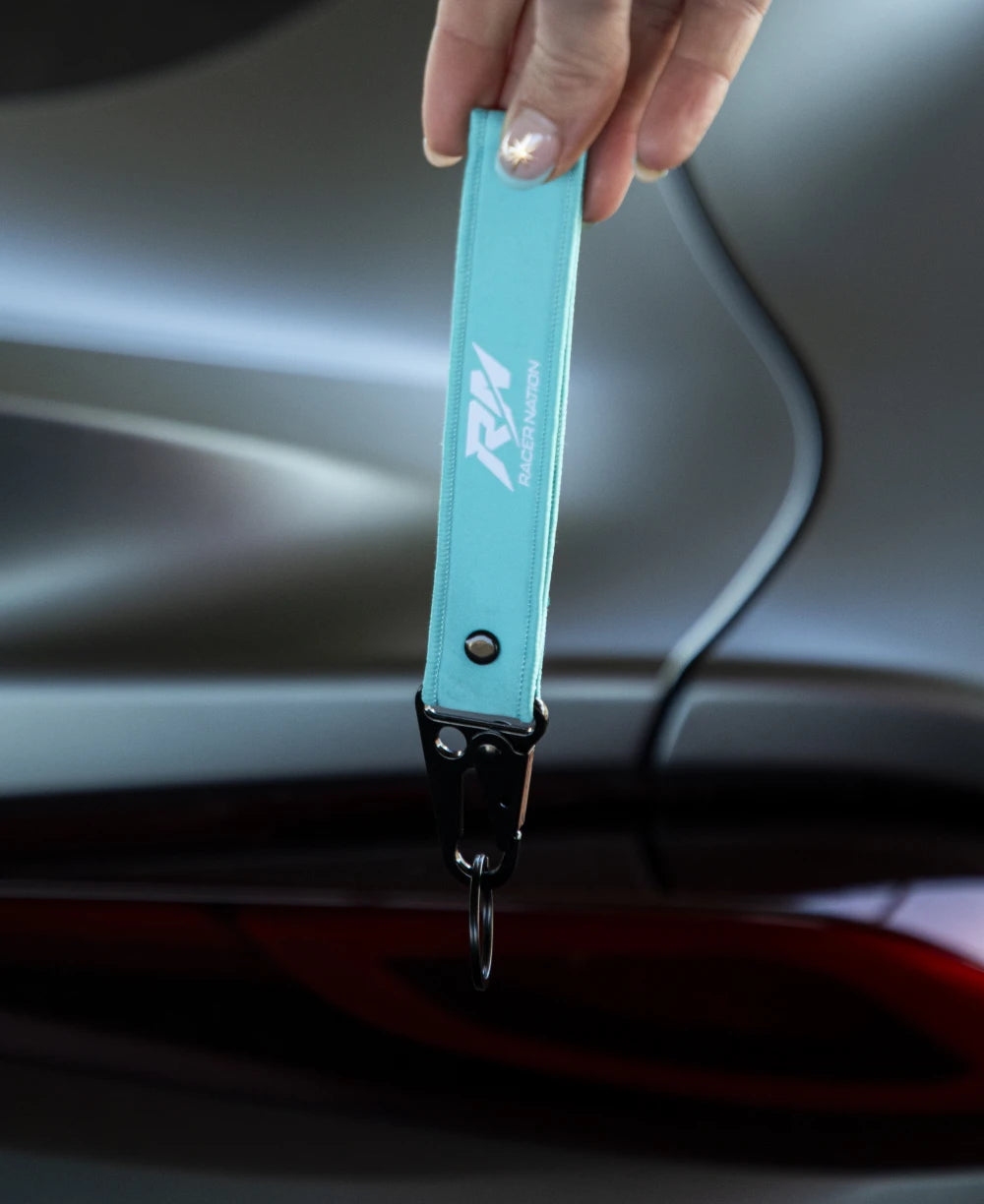 Turquoise Racer Nation fabric keyring featuring the white RN logo and black metal clip.